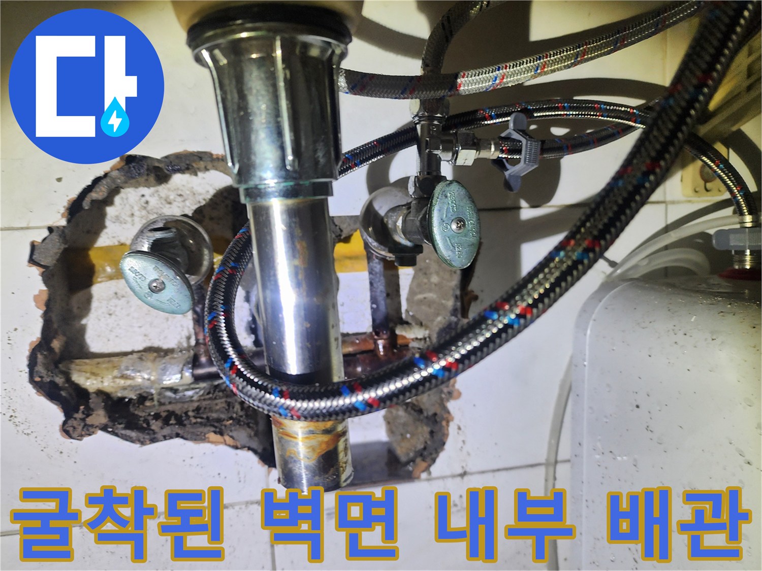타일 아래 숨겨진 노후된 동배관과 부식된 연결 부속의 모습