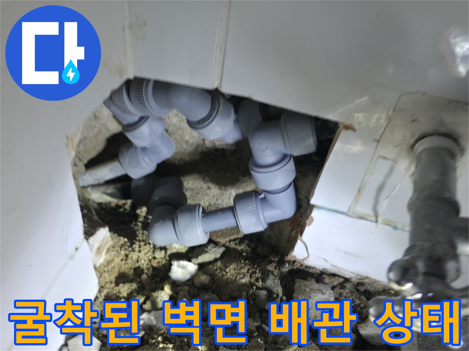 벽 내부의 회색 배관과 금속 밸브가 노출된 모습