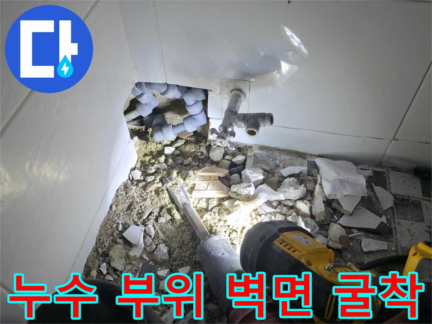 파헤쳐진 벽면 속 수도 연결 부속과 깨진 타일 파편들