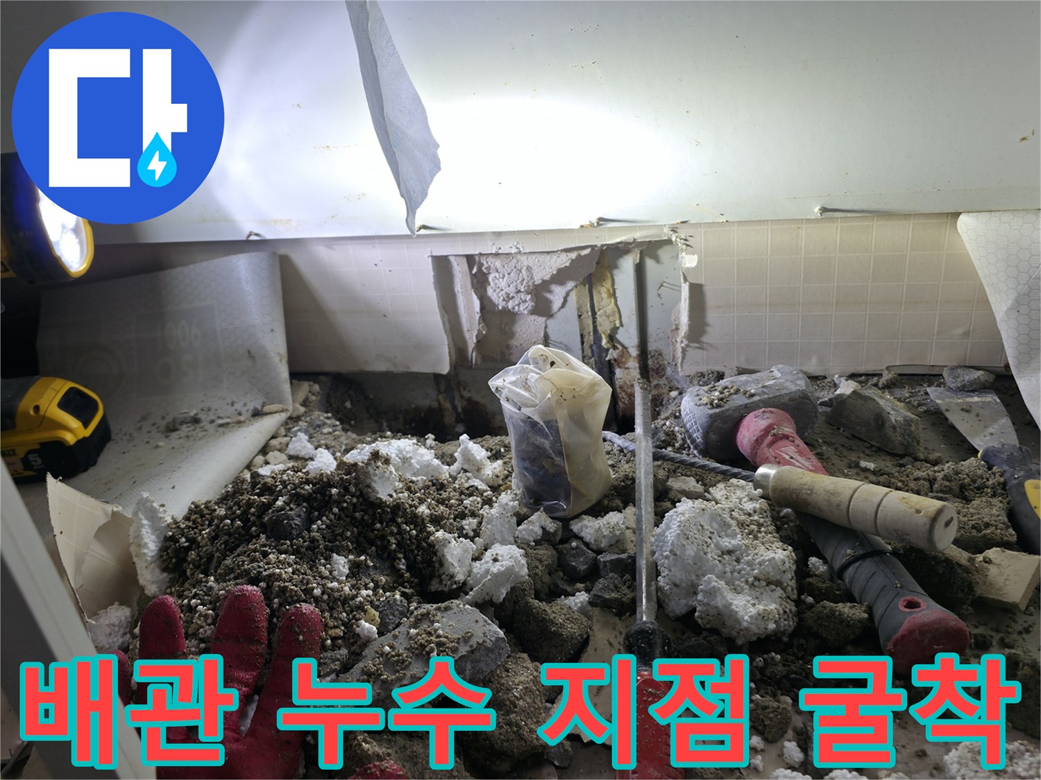 싱크대 하부 바닥을 파낸 후 드러난 배관 주변의 젖은 흙과 장비들입니다.