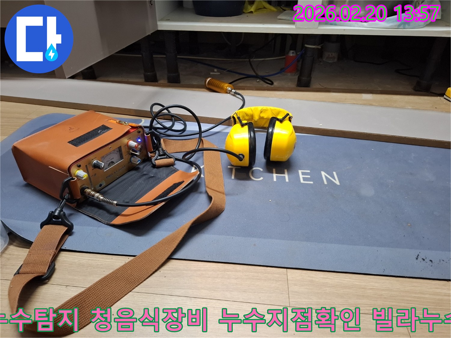 누수 엔지니어가 주방의 숨겨진 배관 누수를 찾아내기 위해-첨단 청음식 탐지 장비를 활용하는 모습입니다-헤드폰으로 미세한 누수음을 감지합니다