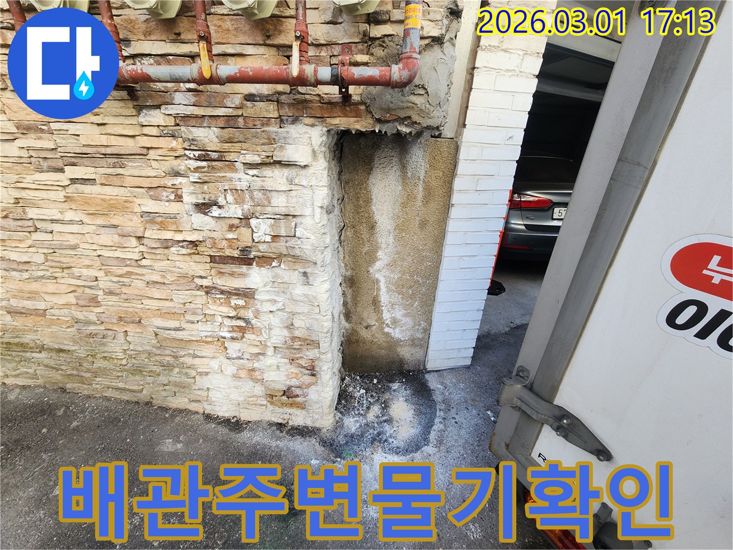 건물 외벽에 설치된-배관 하단부에서-물이 새어 나와-벽면이 젖고-하얗게 백화현상이 진행된-누수 현장