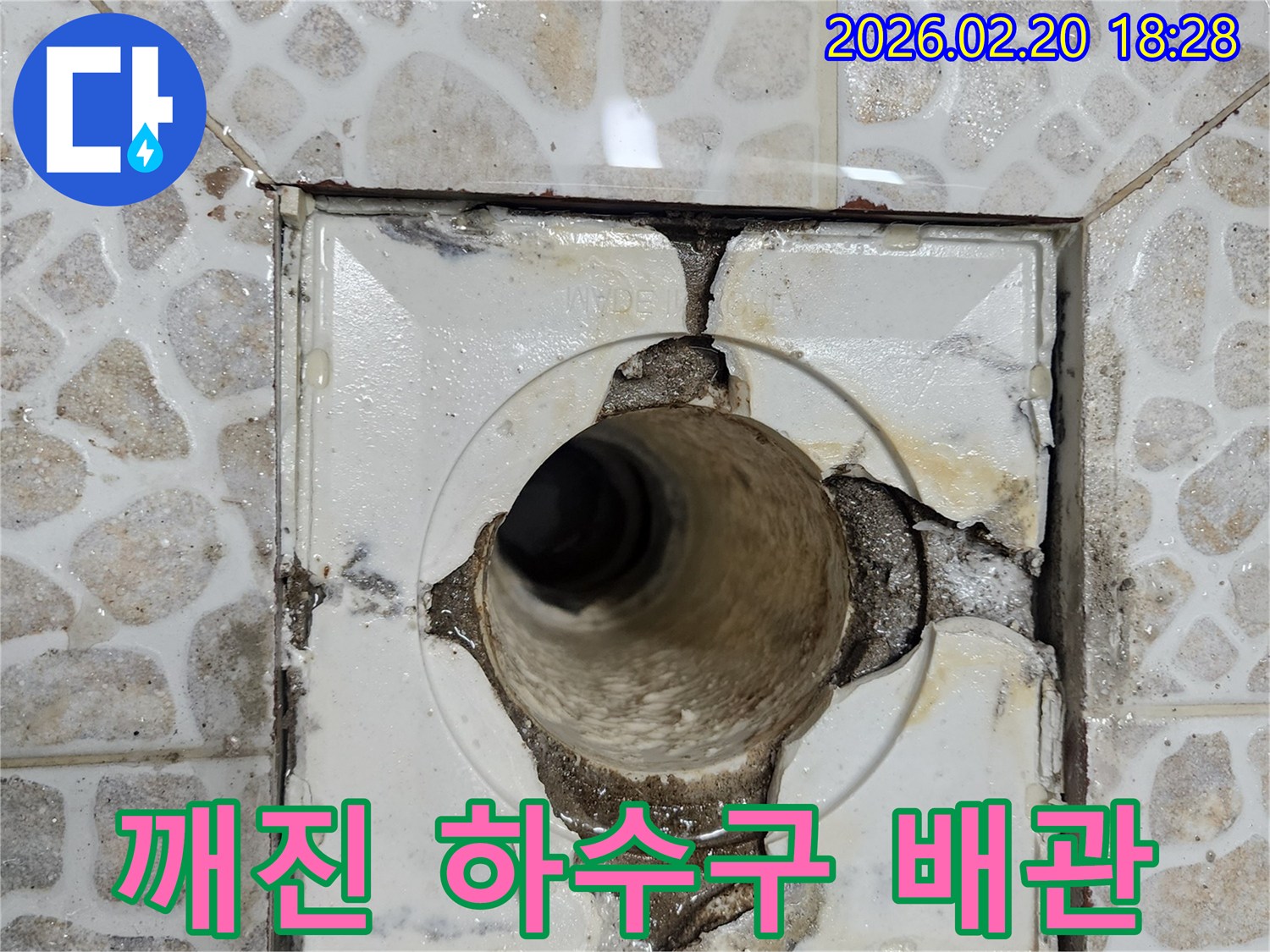 이 사진은-욕실 바닥의 깨진 배수구와-그 주변으로 물이 스며들어-누수가 발생하고 있는-심각한 현장을-보여주고 있습니다