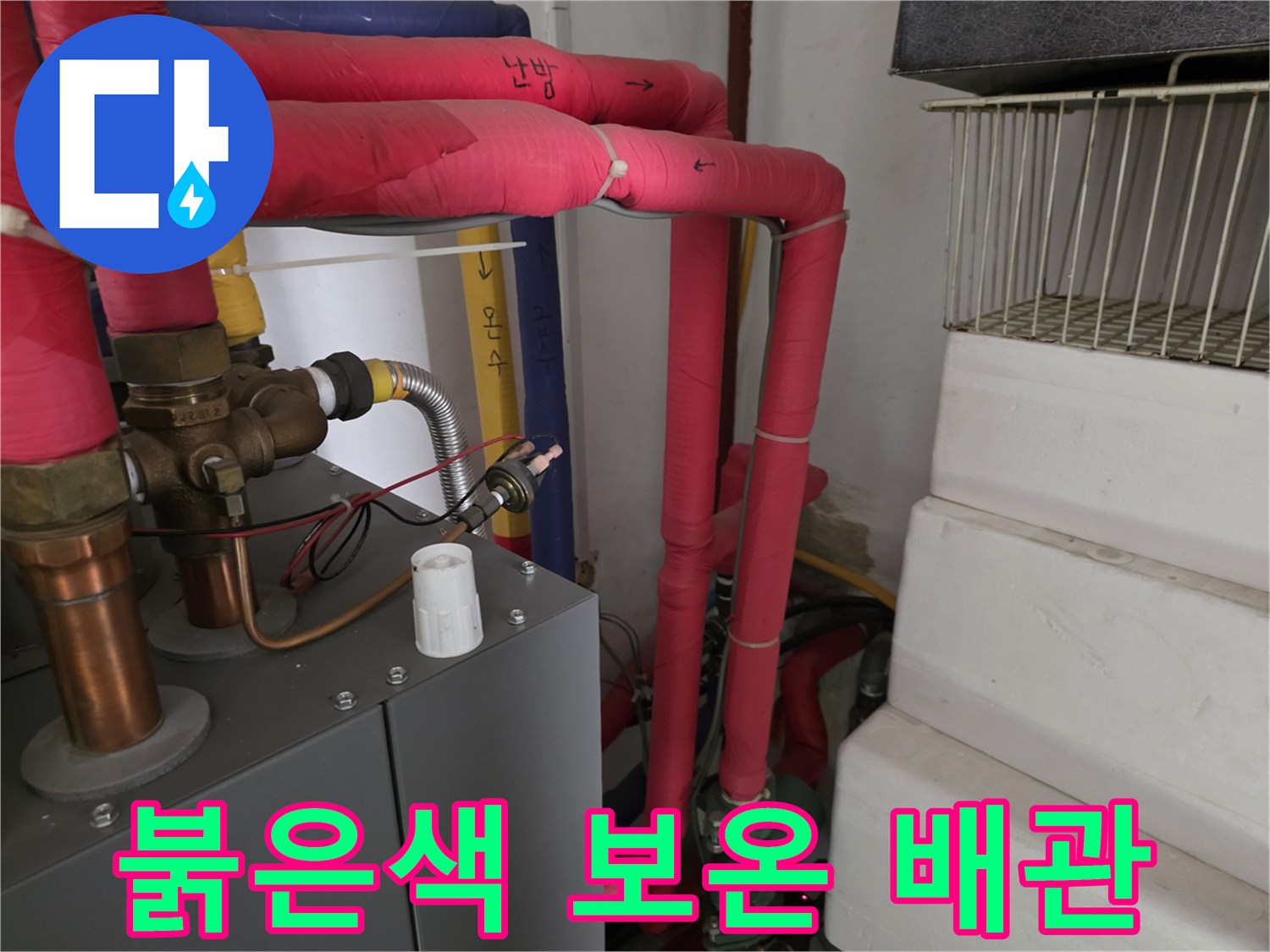분홍색 보온재가 씌워진 난방 배관과 금속 부속품 사진