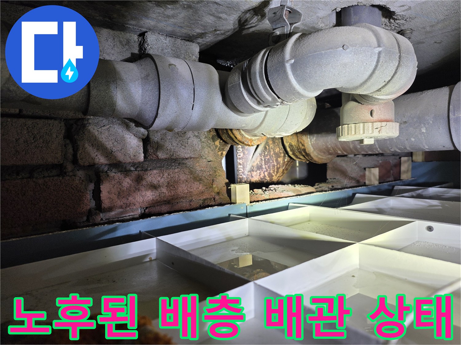 부식된 배관 연결 부위와 젖어있는 벽돌 구조물