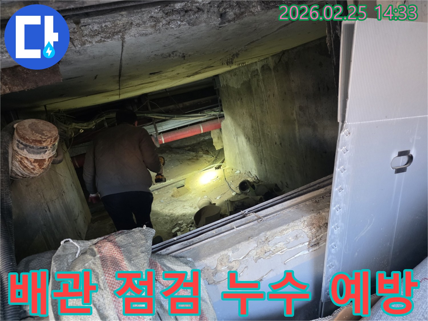 누수 전문 엔지니어가-어둡고 좁은 공간에서-손전등을 비춰가며-배관을 꼼꼼히 점검하여-누수 예방을 위한 노력을-기울이는 모습입니다.