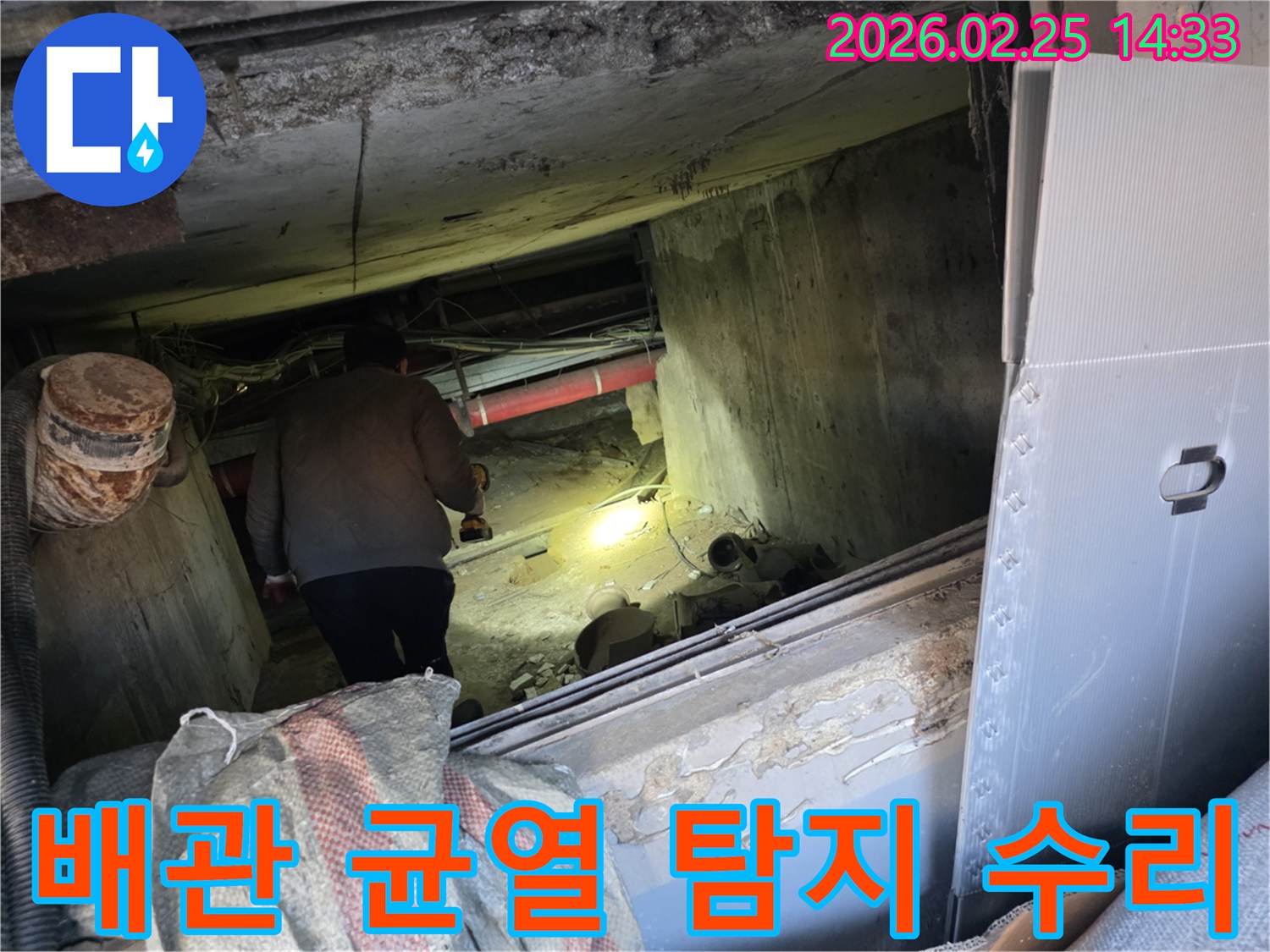 누수 전문 엔지니어가-어둡고 좁은 공간에서-손전등을 비춰가며-배관의 미세한 균열 여부를-정밀하게 확인하여-수리 계획을 세우는 모습입니다.
