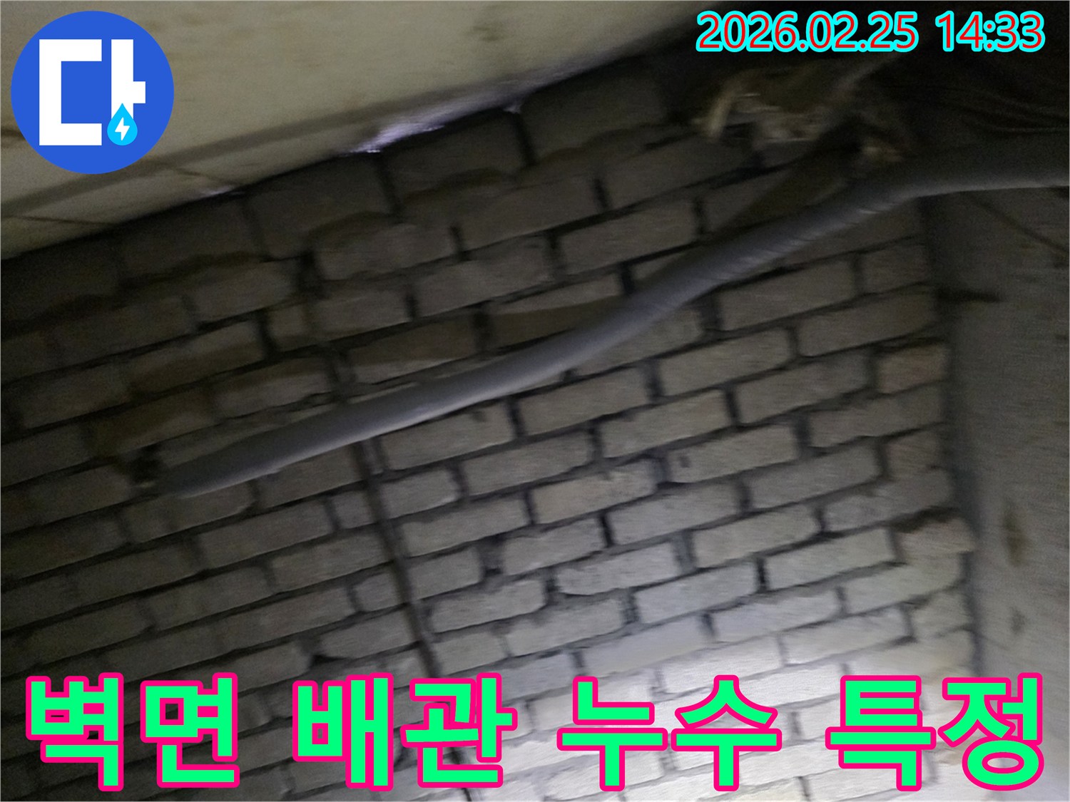 어두운 벽돌 벽면을 배경으로-단열된 배관과 함께-누수 여부를 확인하기 위해-정밀하게 검사되는 현장 모습입니다.
