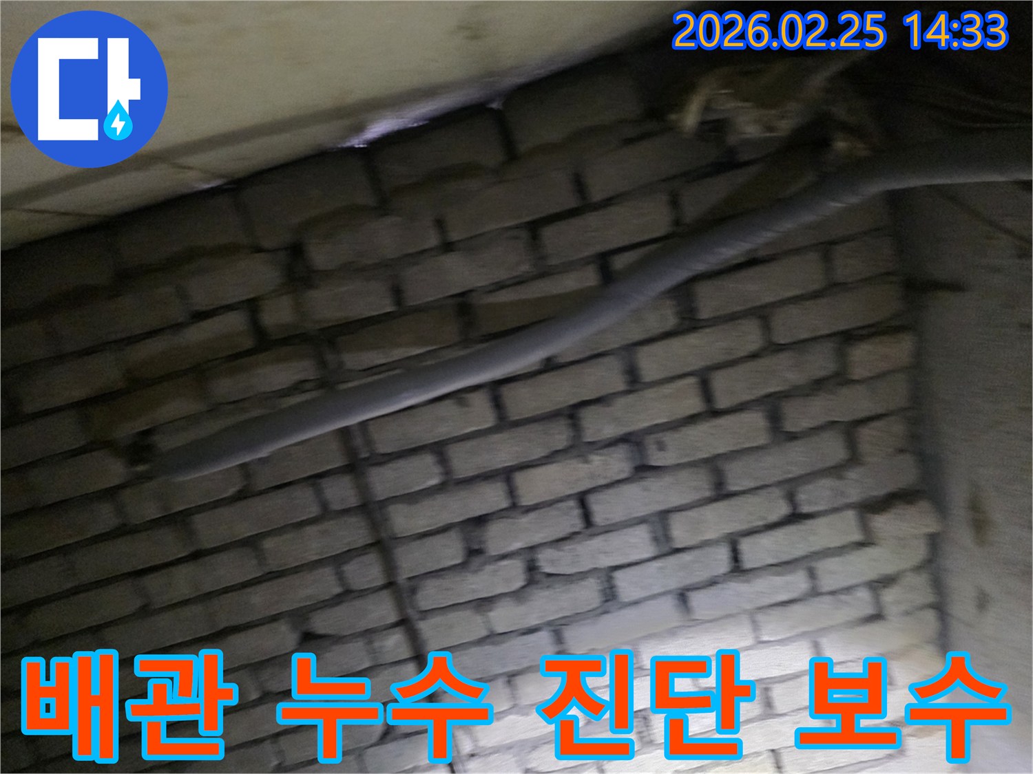 어두운 벽돌 벽면을 배경으로-단열재로 감싸인 배관에서-누수 여부를 정밀 진단하고-보수 계획을 세우는 현장 이미지입니다.