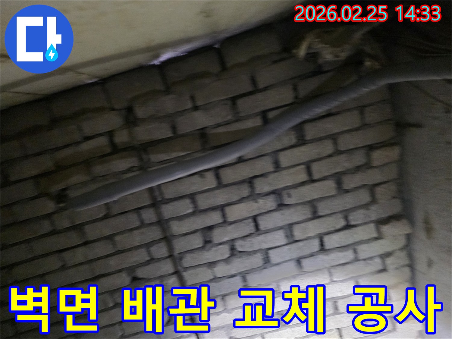 어두운 벽돌 벽면을 배경으로-단열재로 감싸인 배관을-교체하기 위해 촬영된 현장 이미지입니다.