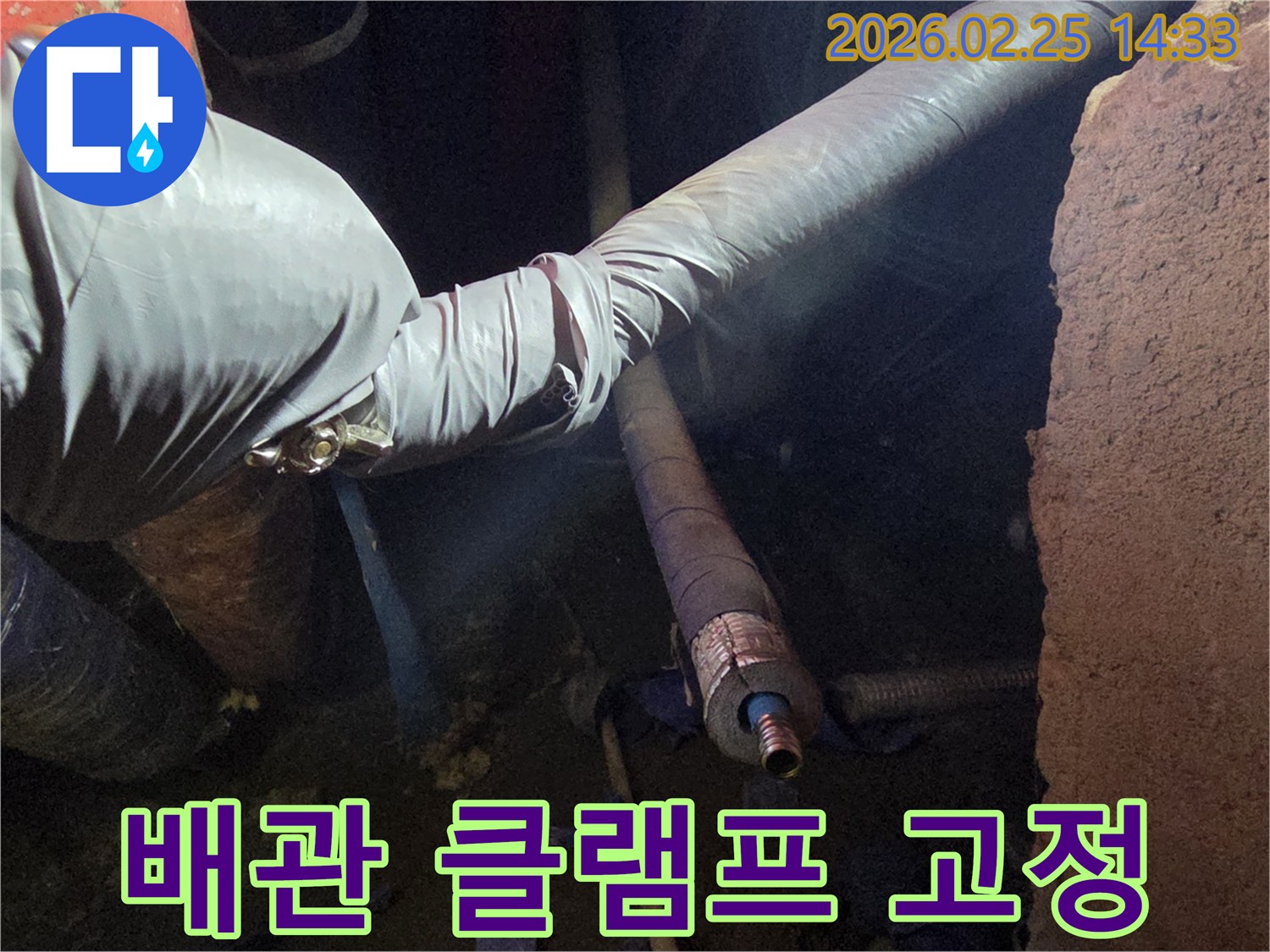어두운 작업 공간에서-장갑을 낀 손이-배관의 연결 부위를-클램프로 단단히-고정하여-강력하게 밀봉하는-모습입니다
