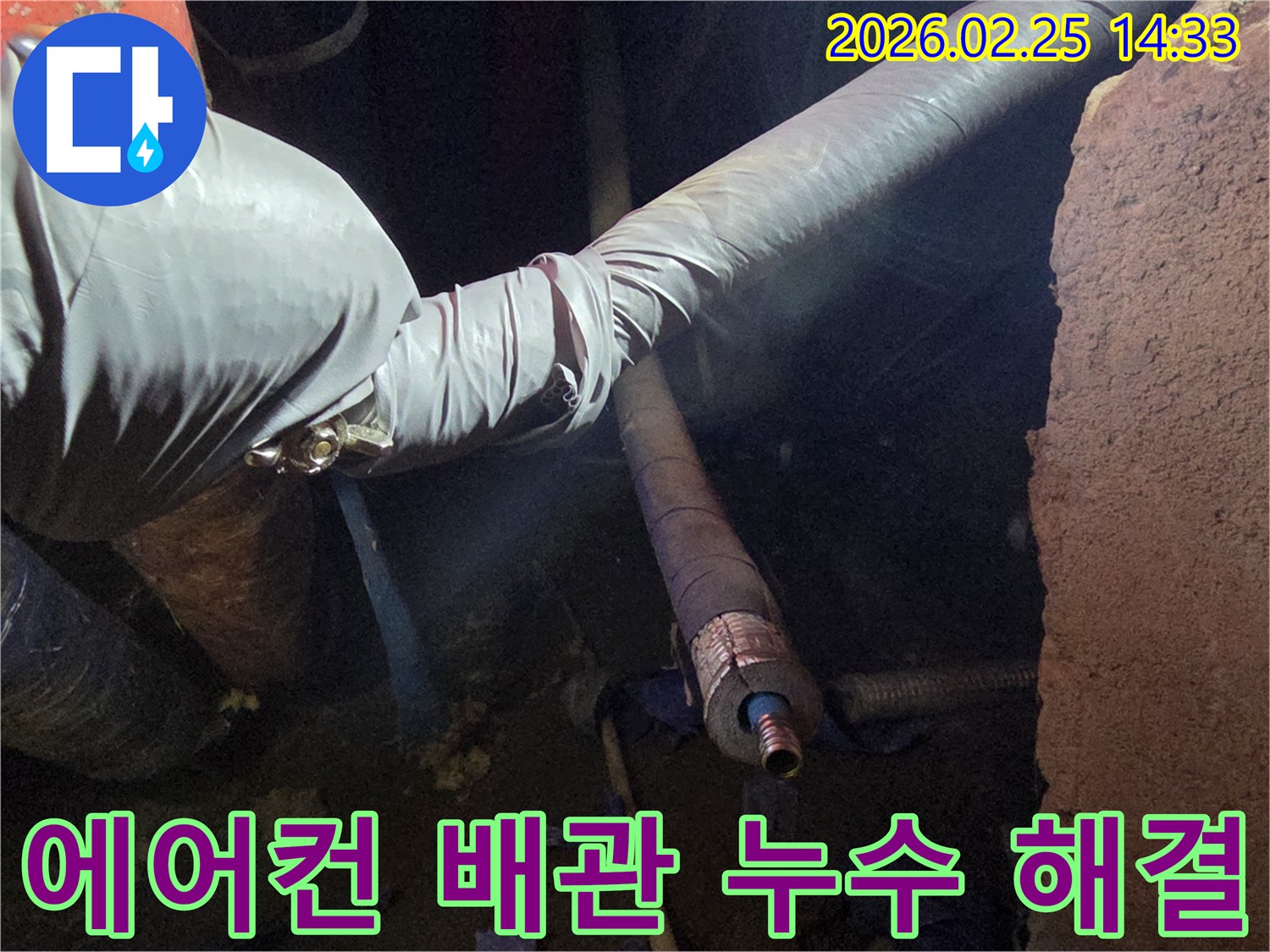 어두운 작업 공간에서-장갑을 낀 손이-에어컨 배관의-손상된 연결 부위를-세심하게 점검하며-누수 문제를-해결하는 모습입니다