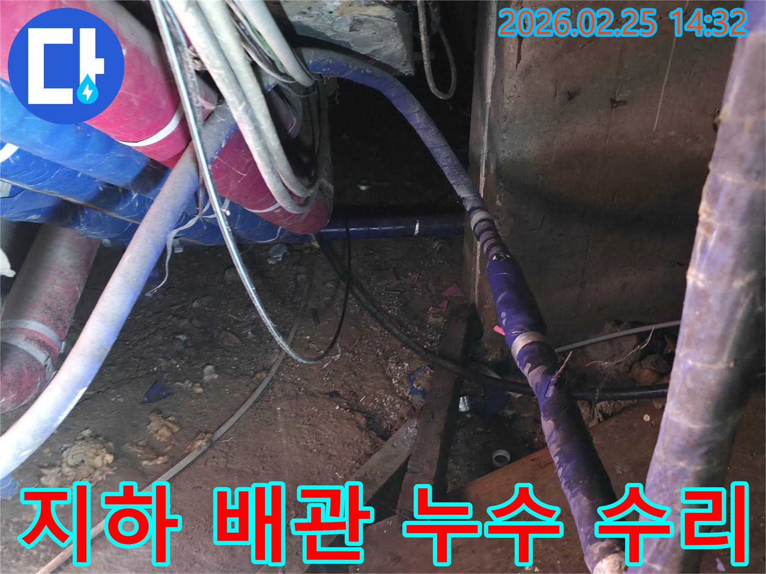 이 사진은 좁고 어두운 지하 공간에서-파손된 수도 배관을-전문가가 교체하는-복잡한 공사 현장을 담고 있습니다.