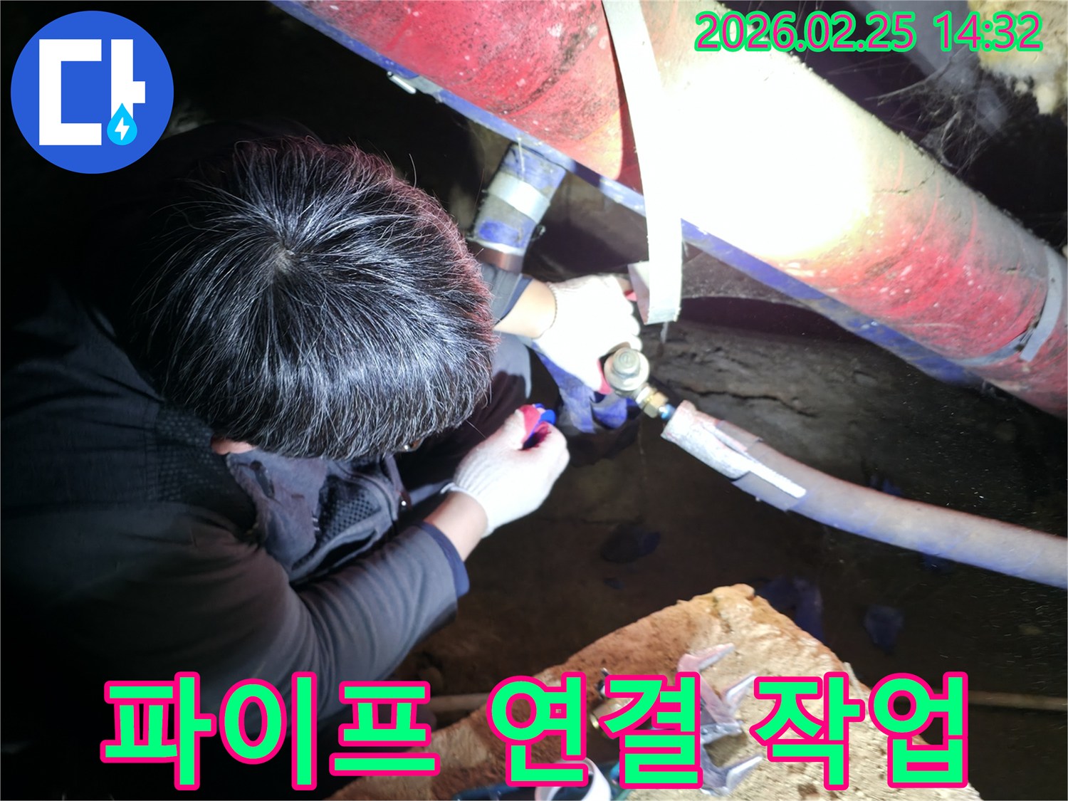 전문 누수 엔지니어가 어두운 작업 공간에서 파이프를 정교하게 연결하며 누수 지점을 보수하고 있습니다-정확한수리-배관전문가