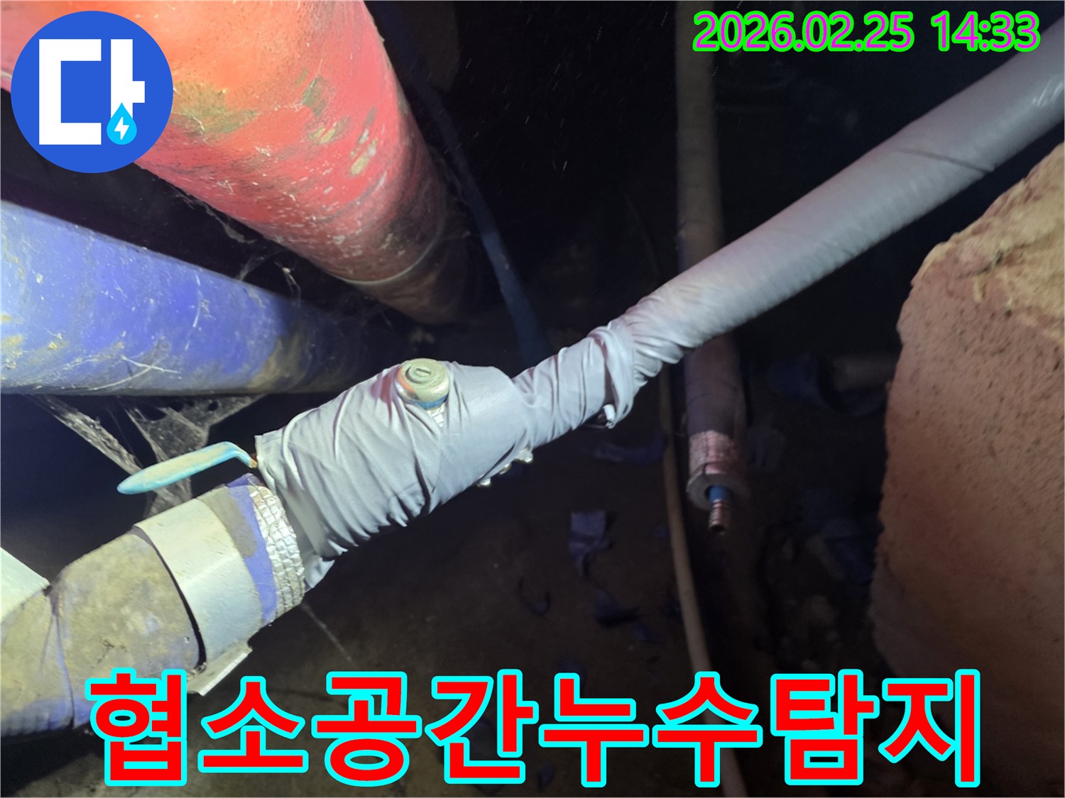 좁고 어두운 상가 배관 공간에서-정밀 탐지 장비를 사용하여-누수 지점을 찾아내는 숙련된 엔지니어의 모습입니다