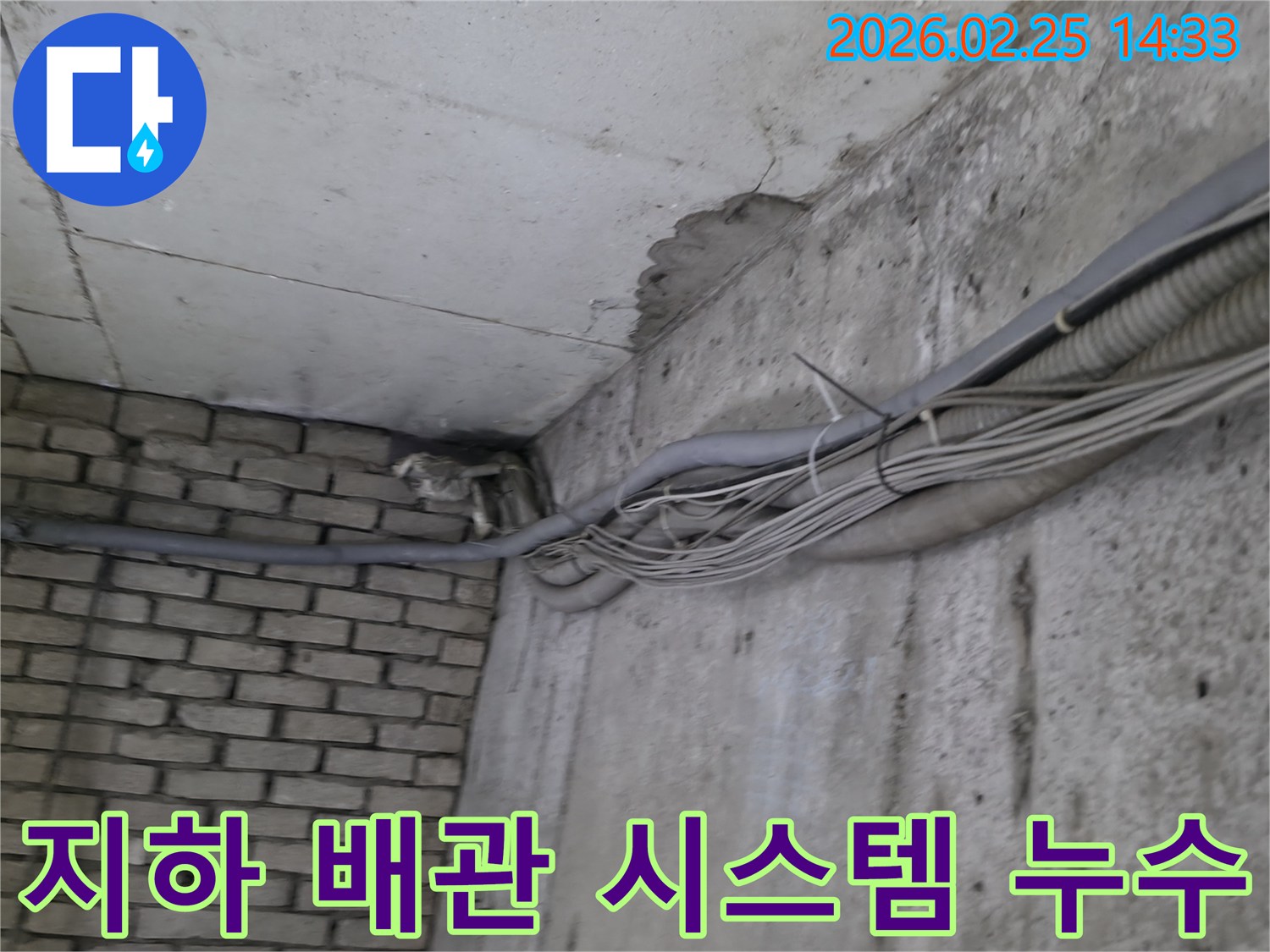 지하 벽면의-콘크리트와-벽돌 벽이 만나는-구석에서-발견된-오랜 누수로 인한-물자국과-복잡한 배관 시스템