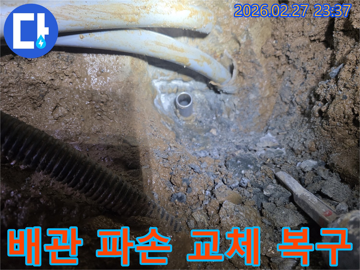흙 속에서 드러난-파손된 배관을 새로운 배관으로 교체하고 원상복구하는 작업 현장