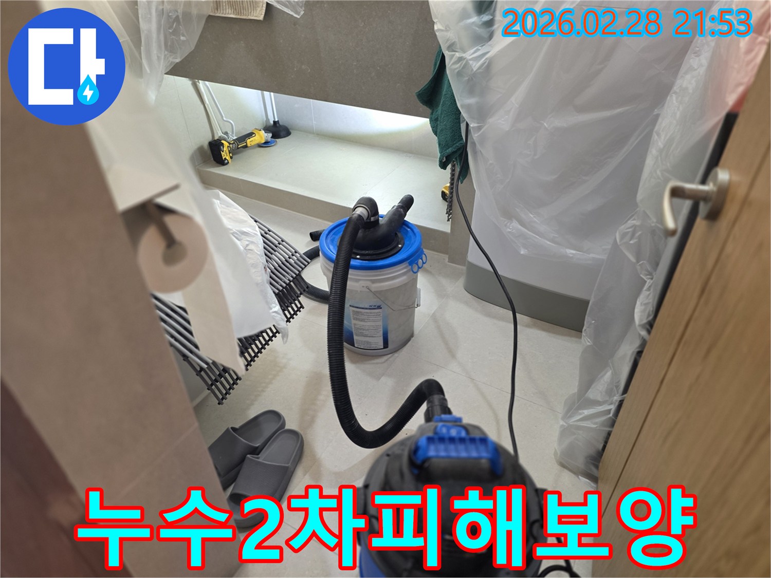 이 이미지는 누수 탐지 작업 시-주변 공간을 비닐로 완벽하게 보양하여-물튀김이나 오염으로부터 보호하고-습식 청소 장비를 준비하는 현장을 보여줍니다.