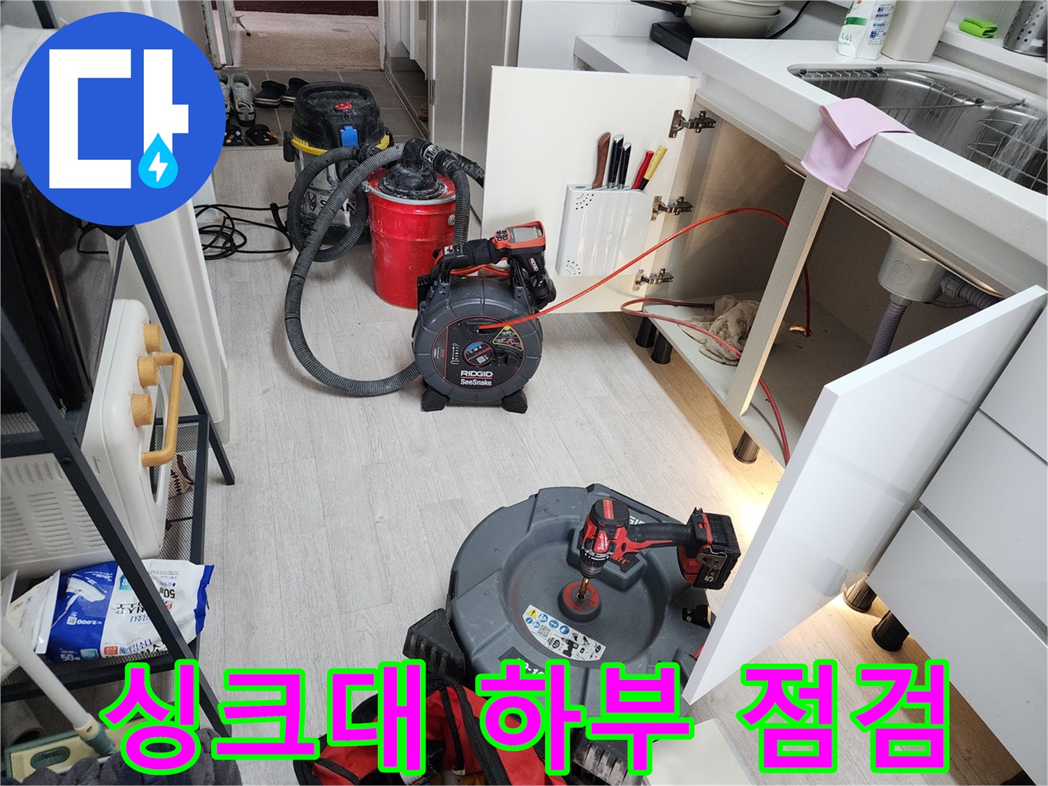 싱크대 하단 배수구 주변의 누수 흔적과 전문 장비 배치