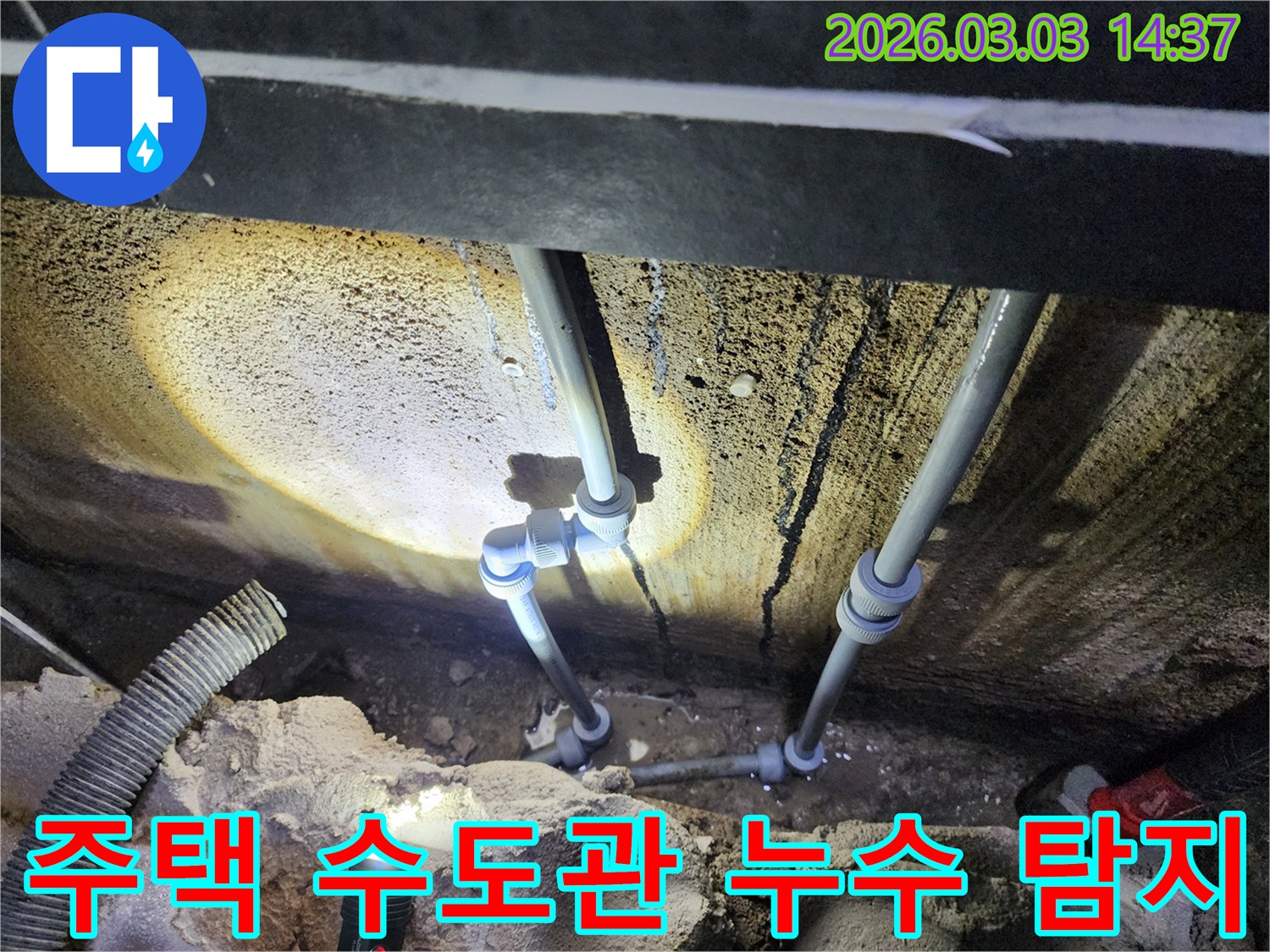 어두운 지하 공간에서-손전등으로 비춘-수도 배관의-누수 흔적을-면밀히 확인하는 모습입니다.