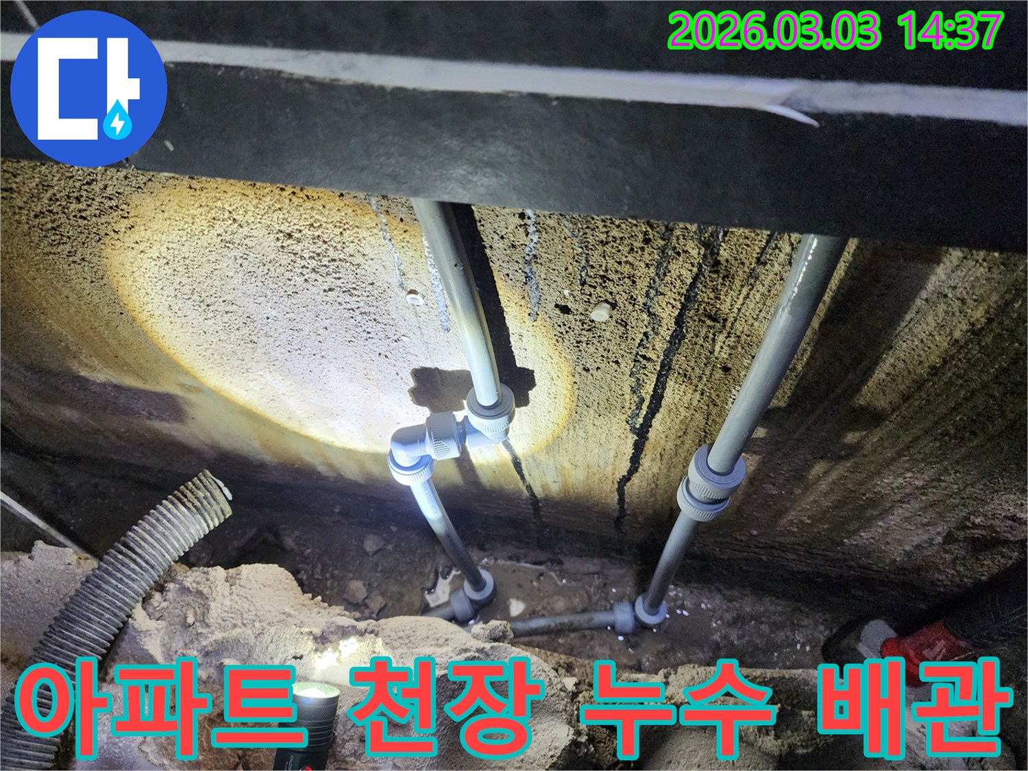 천장 속 어두운 공간에서-손전등 불빛으로-배관 연결부의-누수 지점을-정밀하게 확인하는 모습입니다.