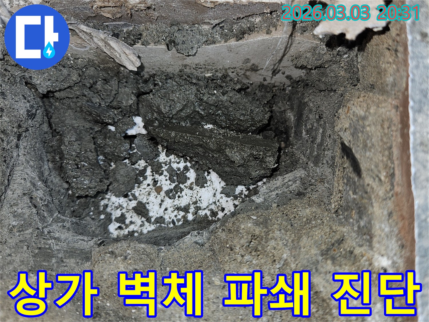 상가 건물 벽체 누수 원인을 파악하기 위해 벽면을 파쇄하고-내부의 젖은 시멘트와 부서진 잔해를 확인하고 있습니다.