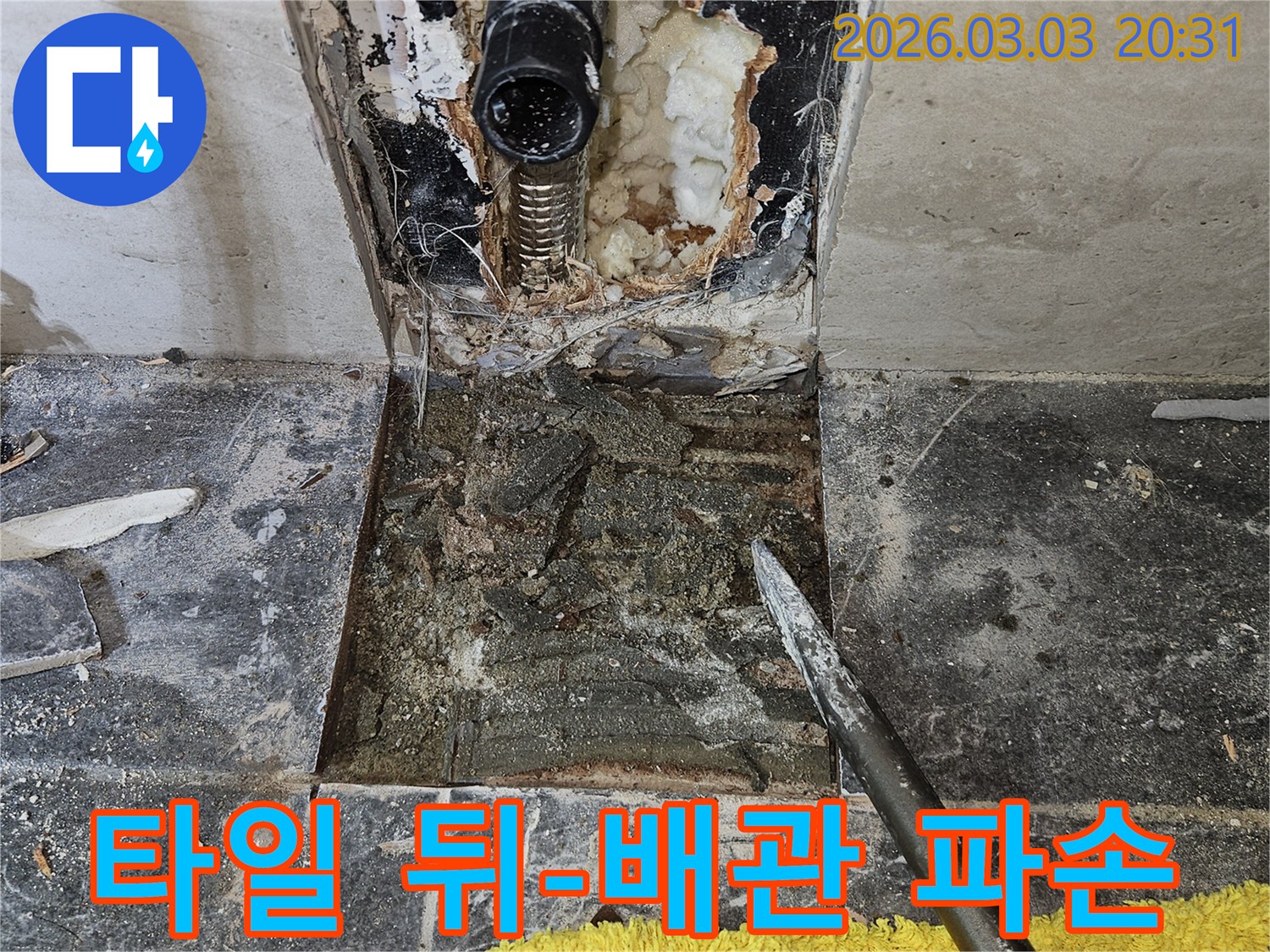 타일 뒤에 숨겨져 있던 배관의 파손으로 인한 누수-문제를 확인하기 위해-타일을 제거하고-손상 부위를 면밀히 검토하는 과정입니다.