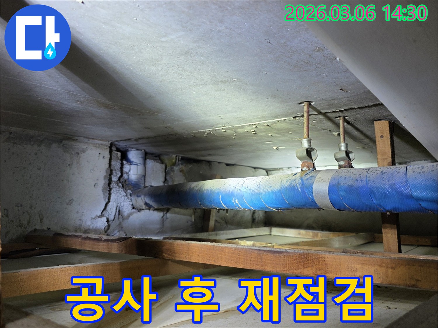 지하 공간의 파란색 배관과-손상된 콘크리트 벽면을-누수 엔지니어가-공사 후 철저한 재점검 시스템을-설명하며 점검하는 모습