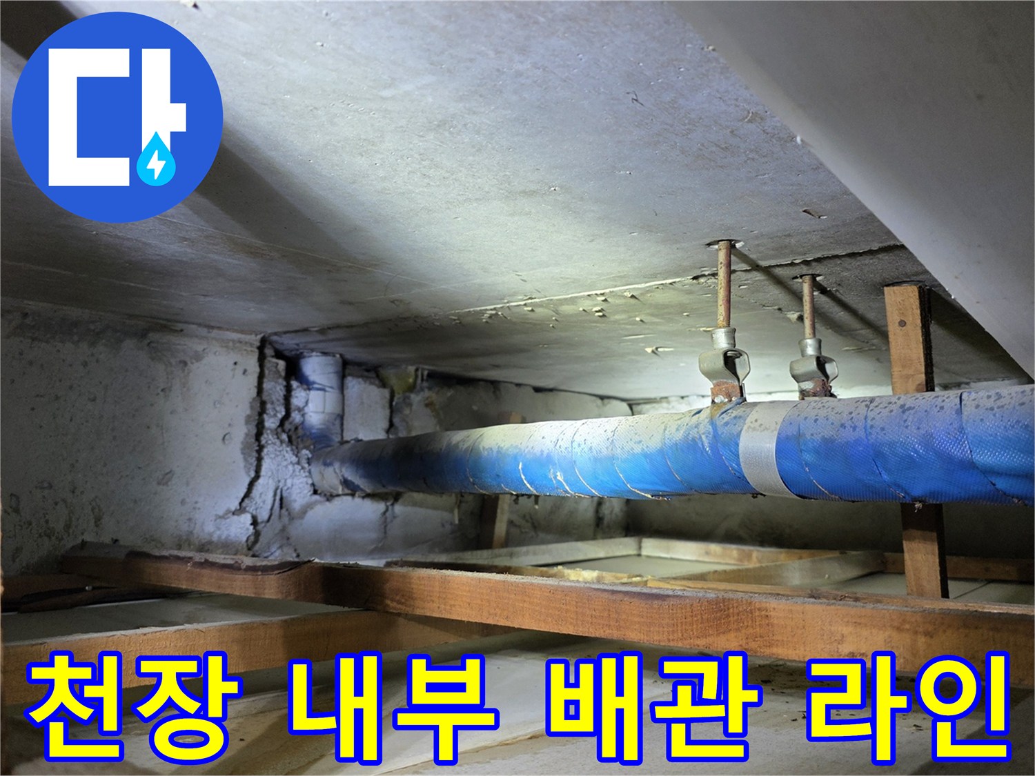 천장 목재 구조물 사이로 지나가는 파란색 보온 처리된 배관 사진