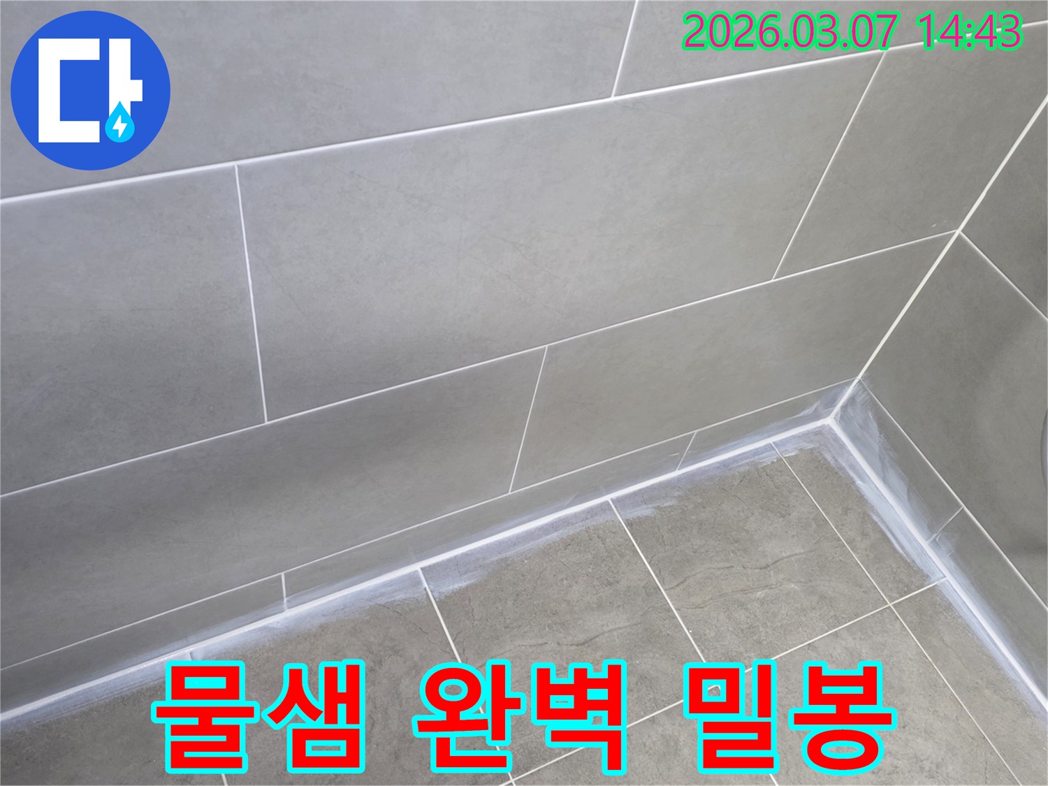 회색 타일로 마감된-주택 욕실의-벽과 바닥 이음새를-새로운 실리콘으로-빈틈없이 밀봉하여-물샘을 완벽히 차단한 모습