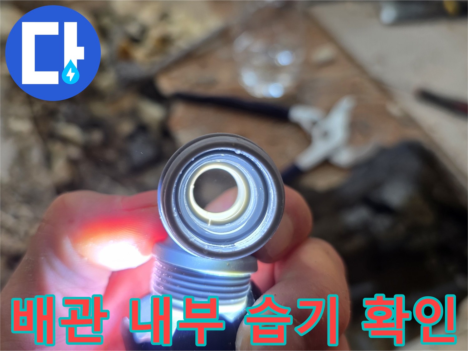 손전등을 활용하여 배관 틈새의 습기를 찾아내는 장면