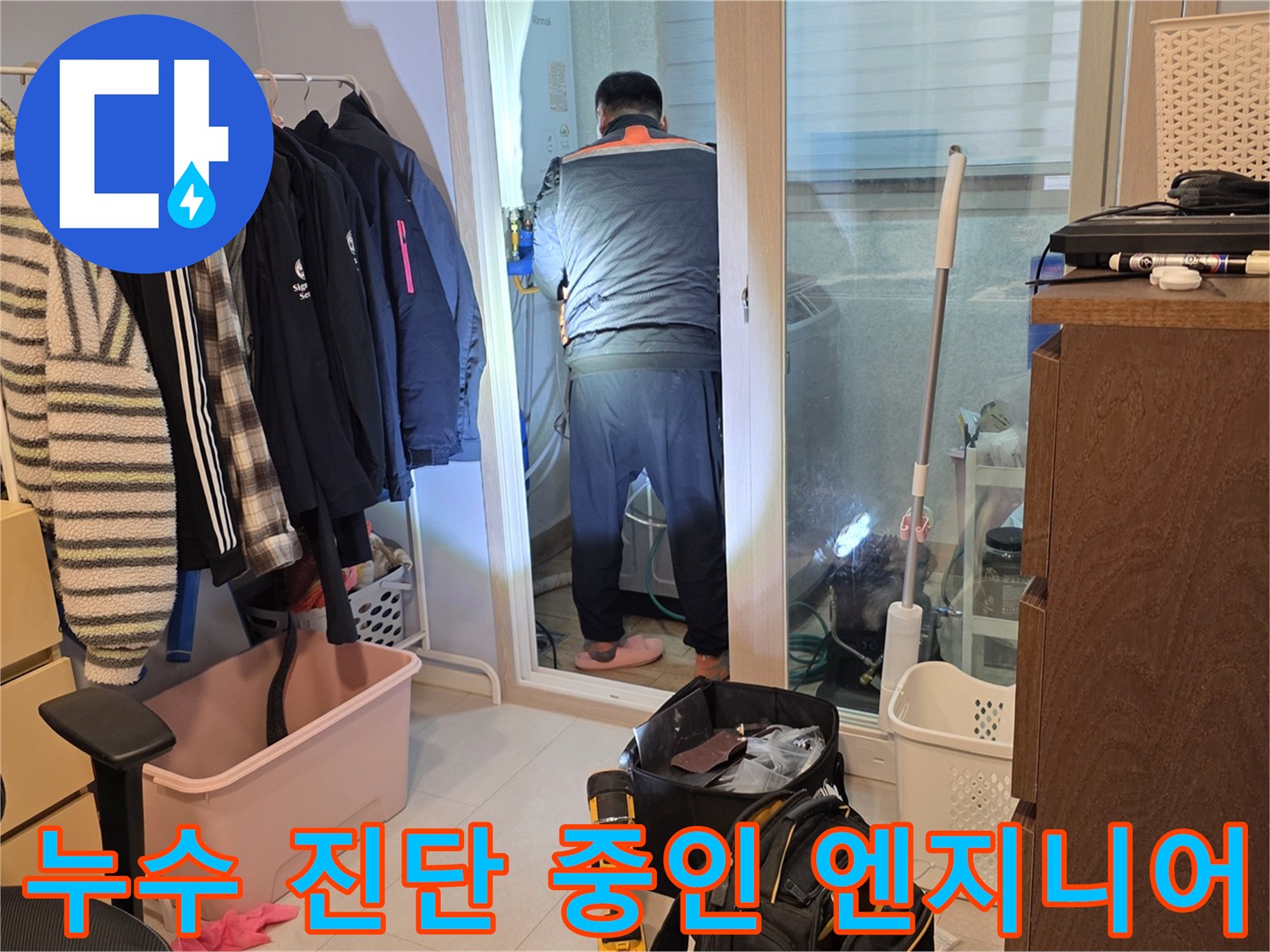아파트 세탁실 내부-배관 누수 여부를 파악하기 위해 전문가가 장비를 준비하며 점검하는 장면입니다.