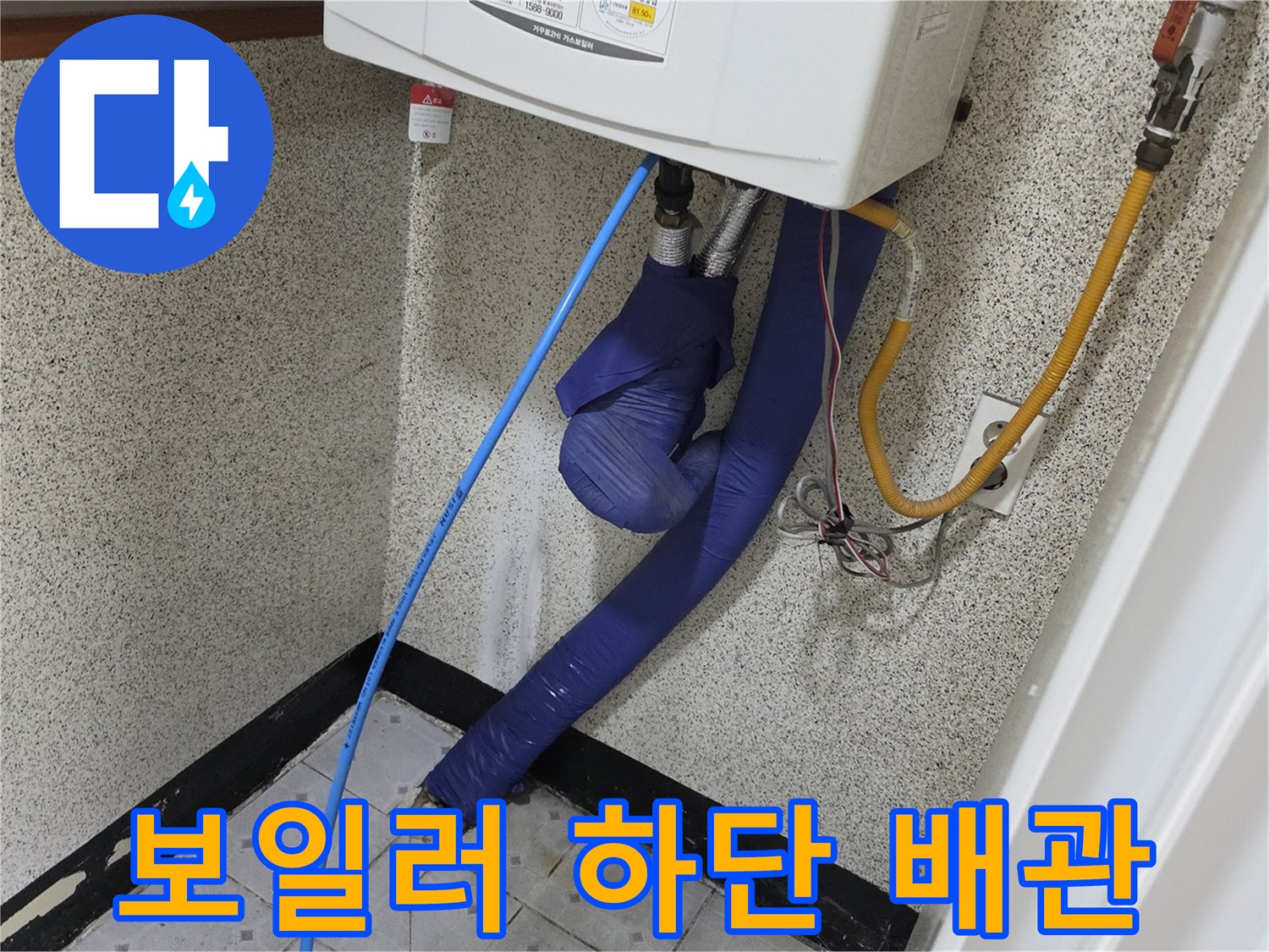 파란색과 노란색 배관이 연결된 보일러실 내부 사진입니다.