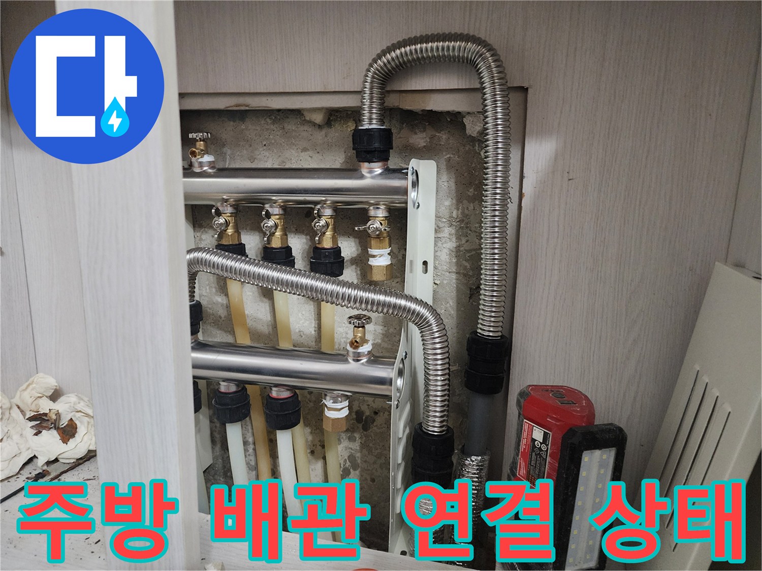 주방 하부장 내부의 배관 연결 부위와 금속 자재 모습