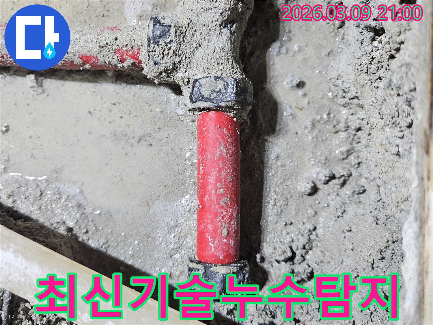 젖은 시멘트 바닥에-매립된 빨간색 배관의-누수 지점을-최신 탐지 기술로-빠르게 찾아낸-모습입니다