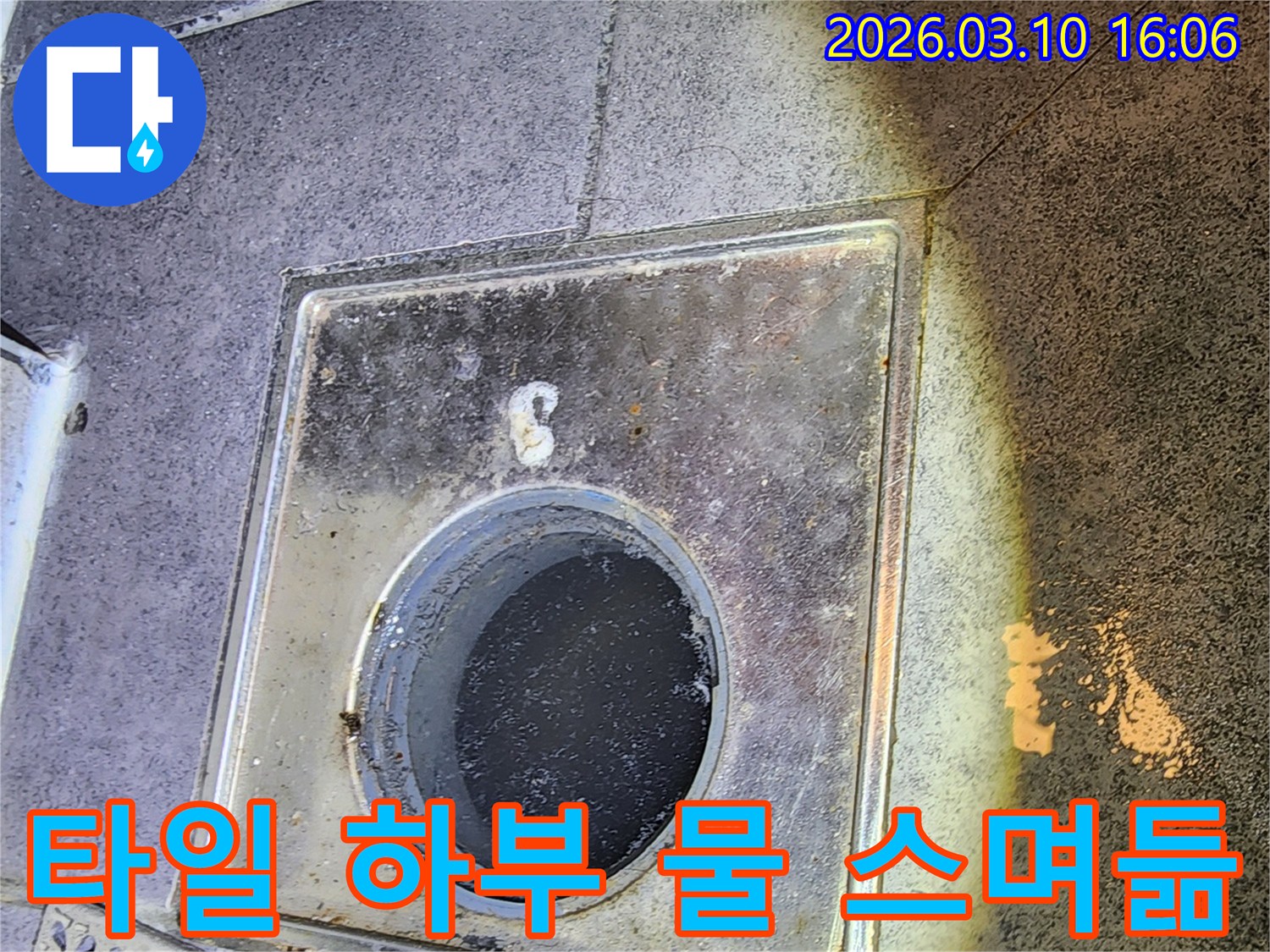 이 사진은-서울 중구의 한 화장실에서-배수구 주변 타일 하부로-물이 스며들었을 가능성을-진단하기 위해-배수구 내부와 주변을-점검하는 현장을 보여줍니다