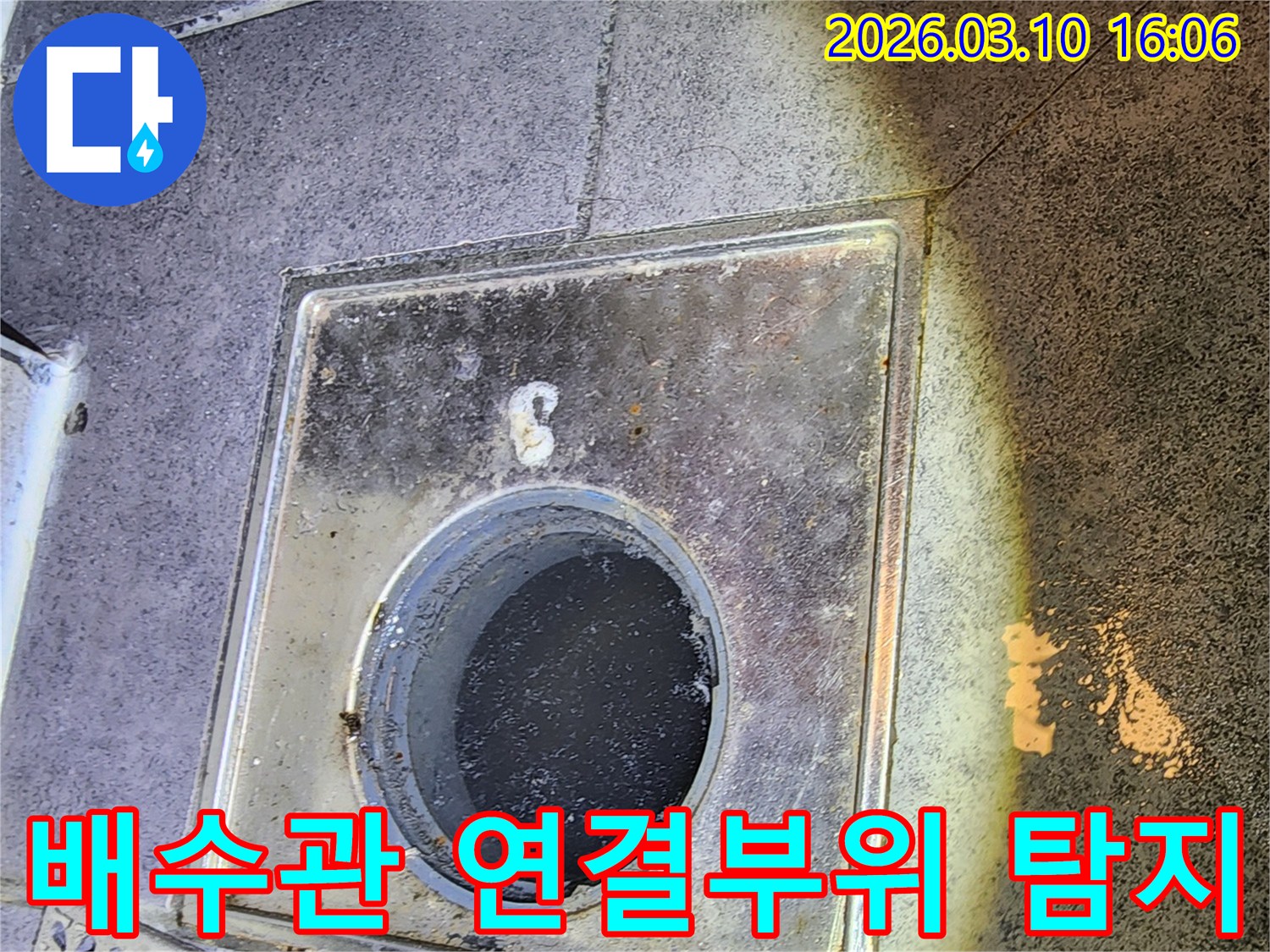이 이미지는-서울 중구의 한 건물에서-바닥 배수구와-배수관의 연결 부위에서-발생할 수 있는 누수를-정밀하게 탐지하는-누수 엔지니어의-모습을 보여줍니다