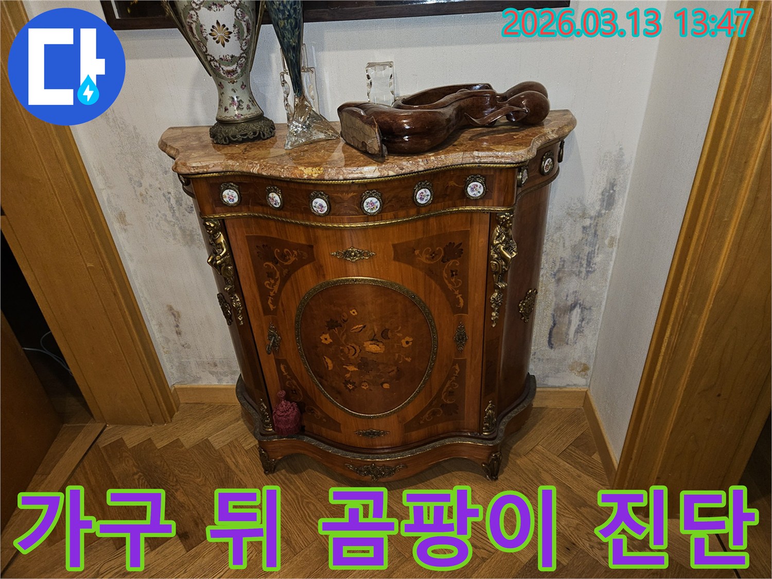 고급스러운 콘솔 가구 뒤-벽에 발생한-누수로 인한-벽지 변색과-곰팡이 흔적을 보여주는 사진