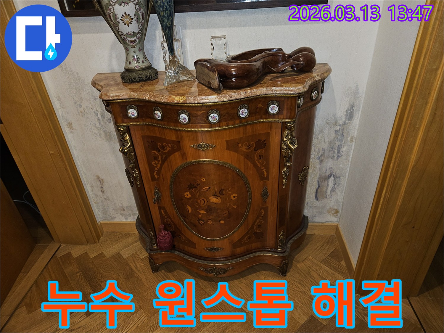 고급스러운 콘솔 가구 뒤-벽에 발생한-누수로 인한-벽지 변색과-곰팡이 흔적을 보여주는 사진