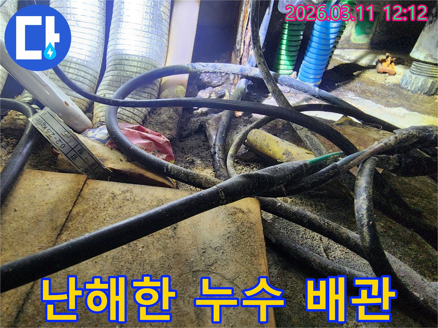 누수-현장에서-복잡하게-얽힌-배관과-전선-사이로-누수-흔적이-보이는-사진입니다.