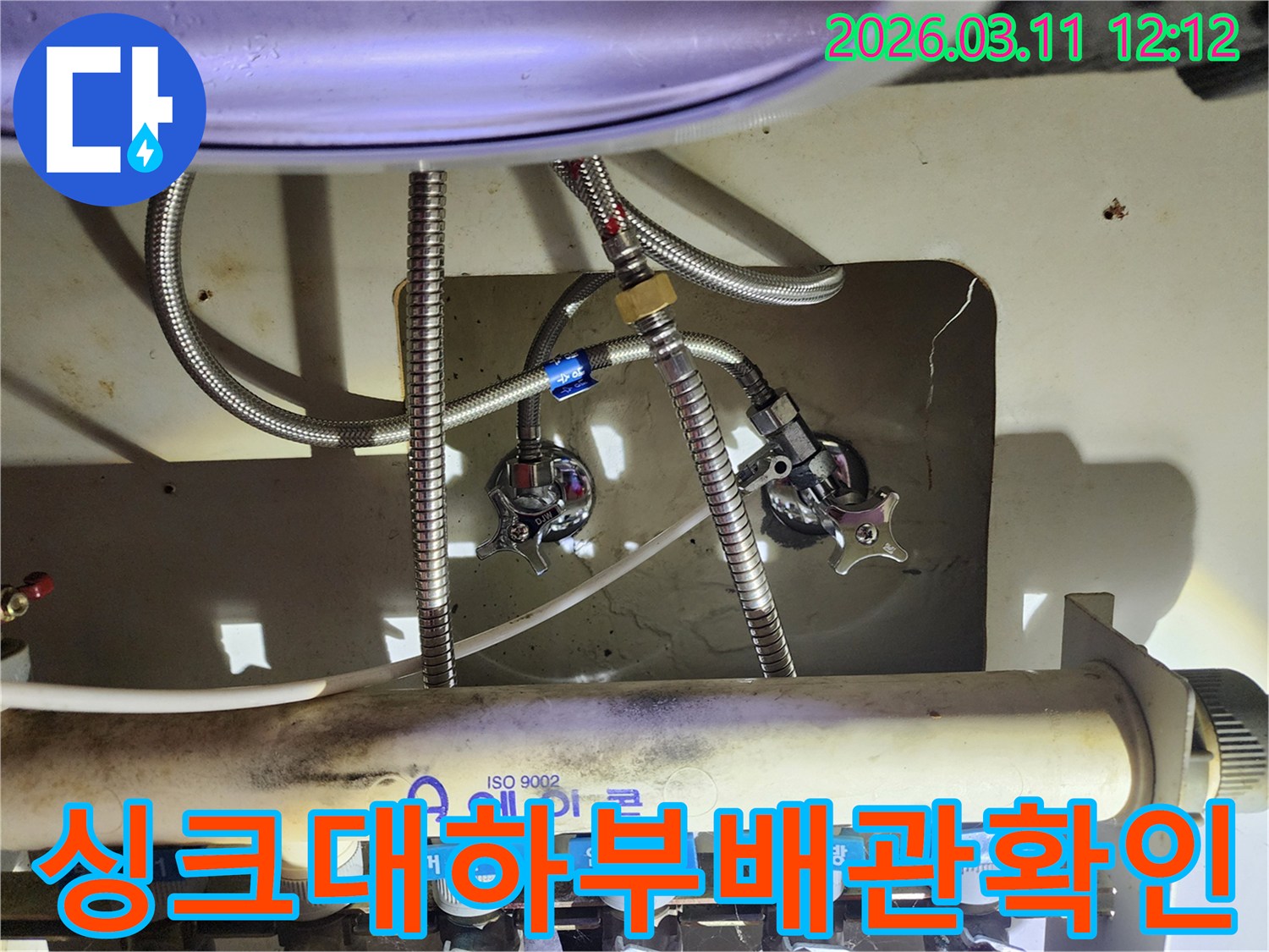 다수의-수도-배관과-밸브가-복잡하게-얽혀있는-싱크대-아래쪽-부분을-확대한-이미지