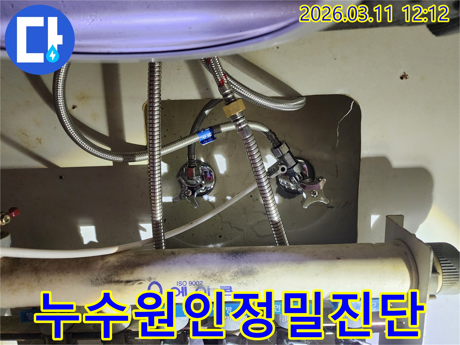 싱크대-아래-설치된-에어컨-배관-분배기와-수도-호스-밸브를-정밀하게-살펴보는-이미지