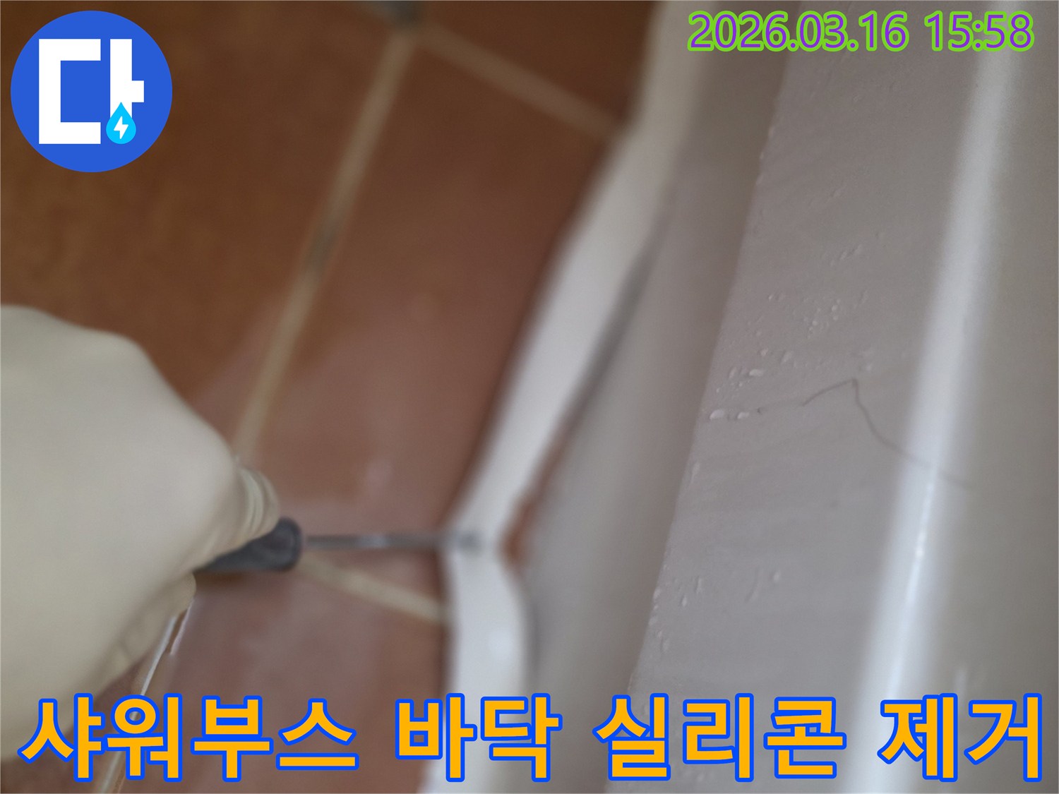 샤워부스 바닥의-오래되고 갈라진 실리콘을-전문가가 제거하는 작업 현장