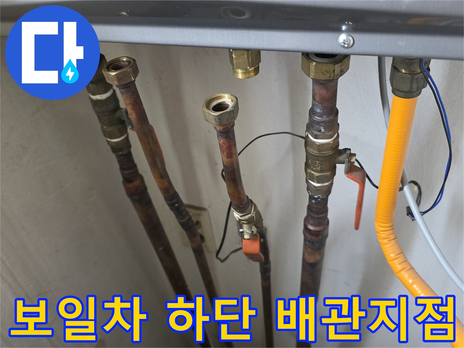 금속 배관과 밸브가 복잡하게 구성된 보일러 하부 모습입니다.
