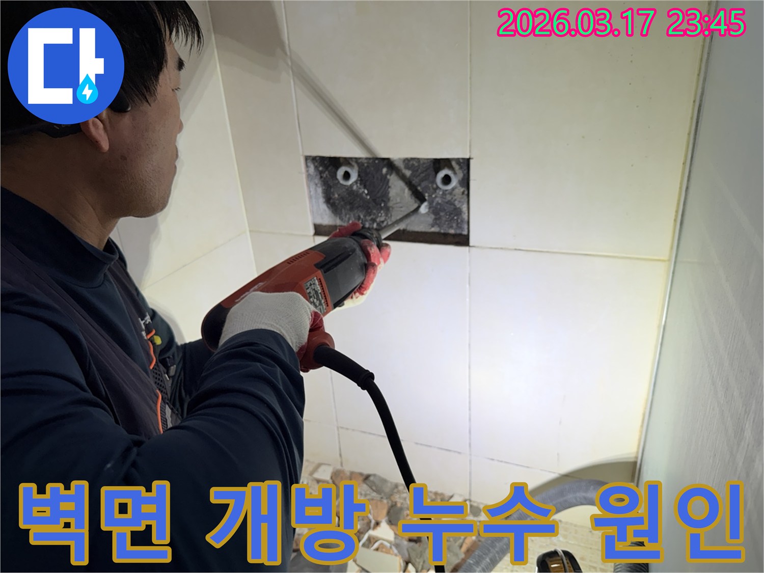 누수 공사 전문가가 욕실 벽면의 타일을 조심스럽게 파쇄하여-누수 원인을 찾기 위한 배관 확인 작업을 진행하는 모습입니다.