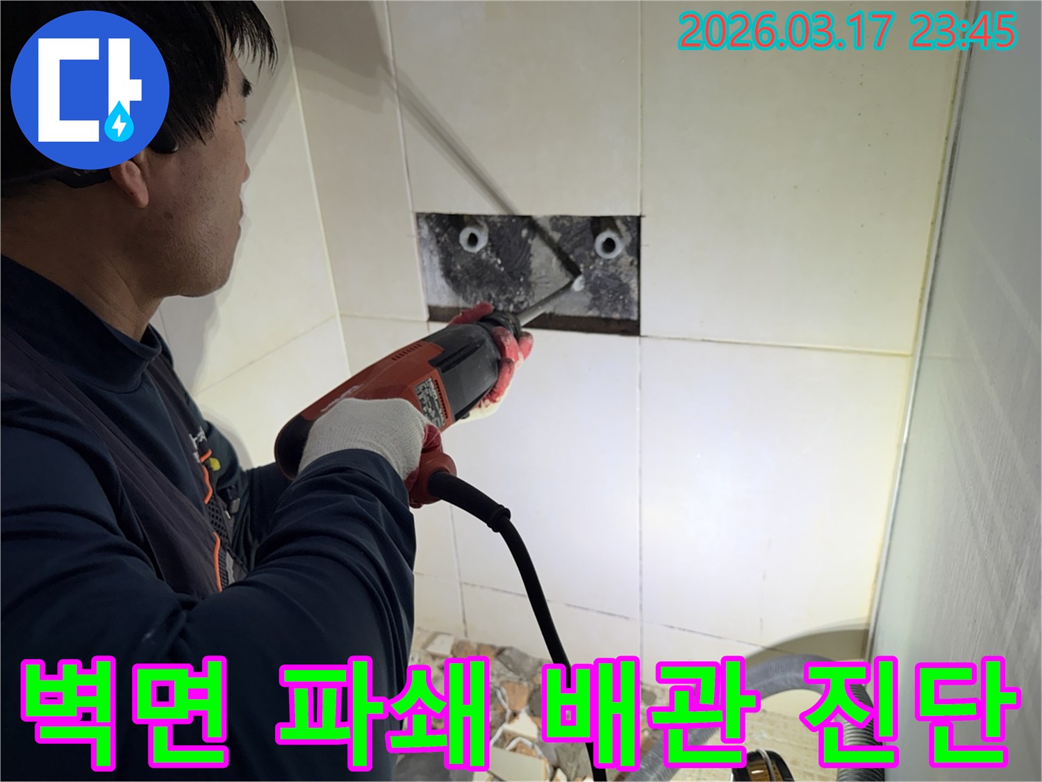 누수 공사 전문가가 주택 욕실 벽면의 타일을 조심스럽게 파쇄하여-누수 원인을 찾기 위한 배관 정밀 진단 작업을 진행하는 모습입니다.
