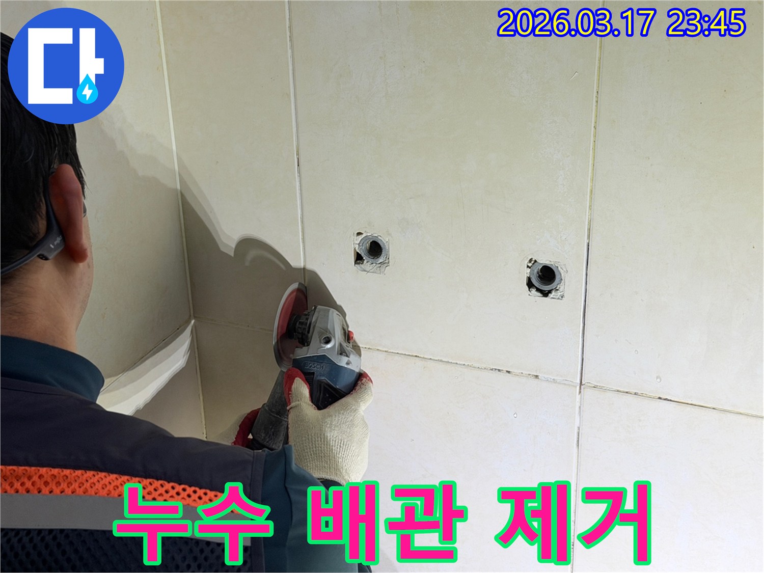 누수된 배관을-노출시키기 위해-전문가가-타일 벽면을-그라인더로-조심스럽게-제거하고-있습니다