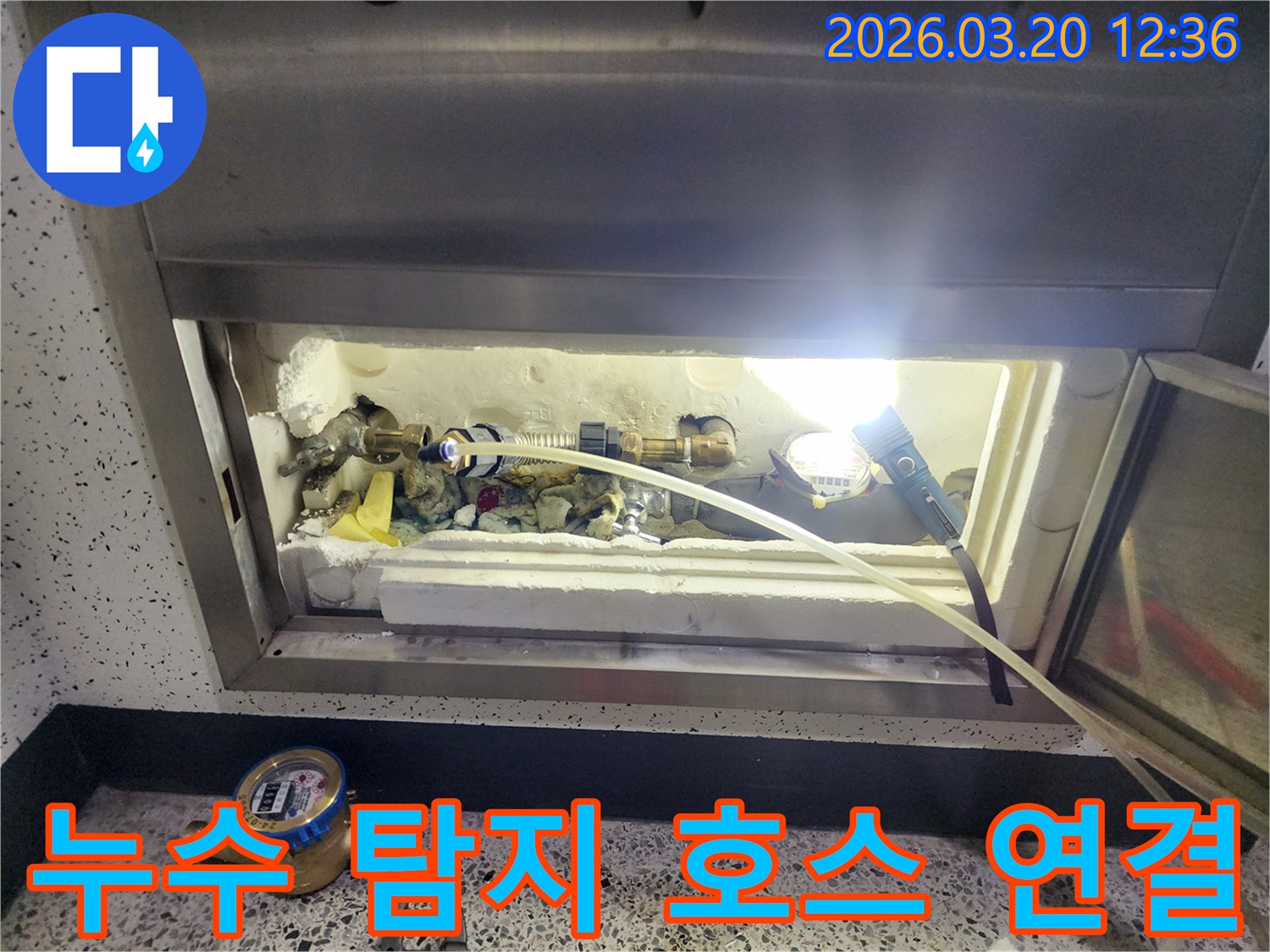 덕양구-온수관-누수-현장에서-정밀-탐지를-위해-배관에-탐지-호스를-연결하여-압력을-확인하는-모습입니다.