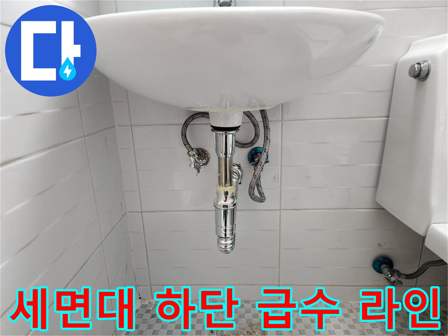 세면대 아래쪽의 은색 밸브와 연결된 유연한 금속 호스입니다.