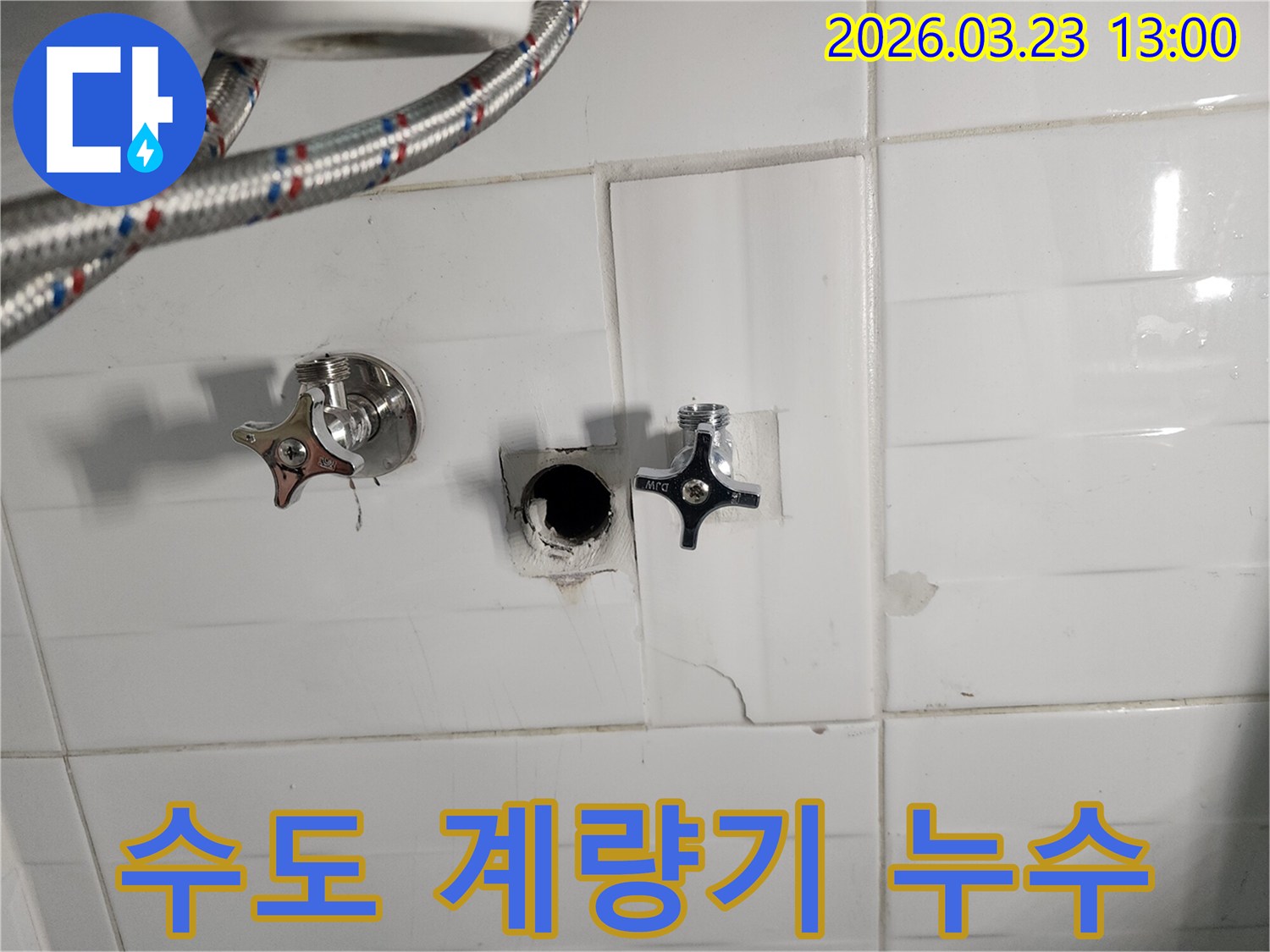 하얀색 타일 벽면의-수도 계량기 연결 부위에서-누수가 확인되어-타일을 제거하고-배관을 점검하는-수도 계량기 누수 현장입니다.